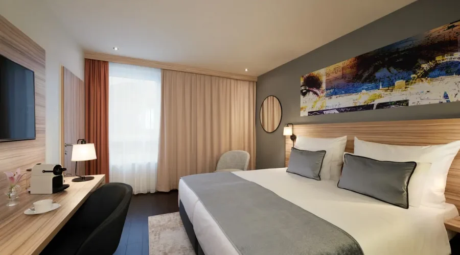 Hotelzimmer mit Doppelbett, großformatigem Wandbild, Fernseher und Schreibtisch mit Kaffeemaschine